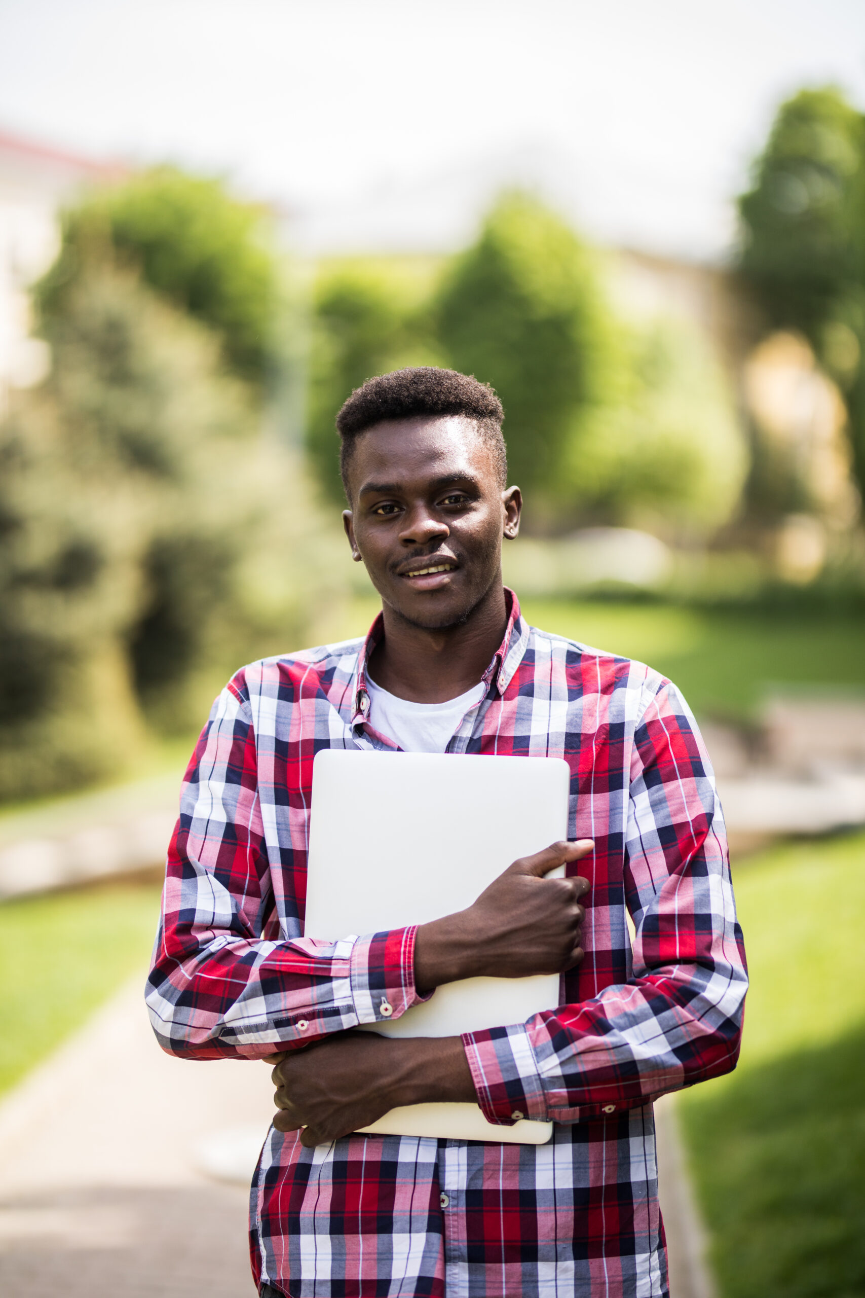 African American college student with laptop in the sunny day on the street